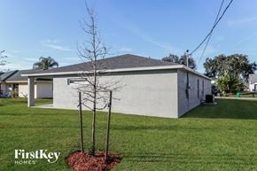 Port St. Lucie house for rent - the front of a white house with a yard and two trees