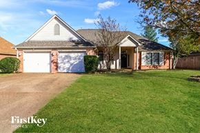 Cordova house for rent - A house with a garage and a tree in front.