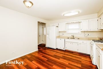 Calumet City house for rent - a kitchen with white cabinets and a wood floor