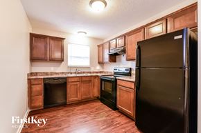Greenwood house for rent - a kitchen with black appliances and wooden cabinets
