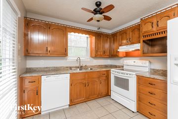 Trussville house for rent - A kitchen with wooden cabinets and white appliances.