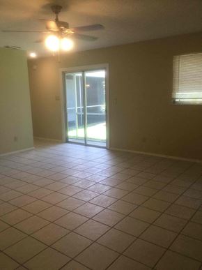 Port St. Lucie house for rent - an empty living room with a tile floor and a sliding glass door