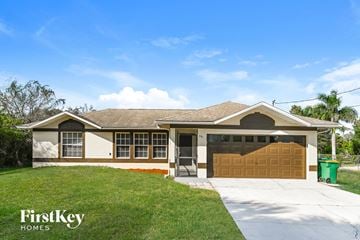 Naples house for rent - a house with a garage door and a lawn