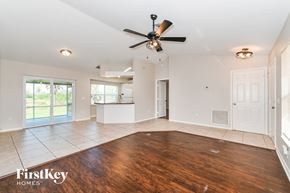 Naples house for rent - an empty living room with a ceiling fan and a kitchen
