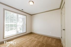 Jonesboro house for rent - a bedroom with a large window and white walls and carpet