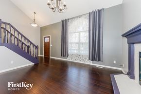 Raymore house for rent - an empty living room with a staircase and a window with curtains