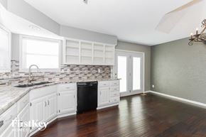 Raymore house for rent - a kitchen with white cabinets and a black dishwasher