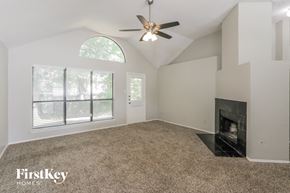 Mckinney house for rent - A spacious room with a fireplace and a ceiling fan.