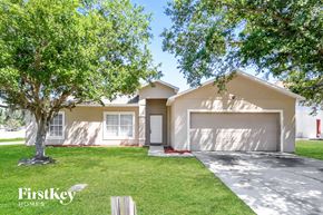 Kissimmee house for rent - a beige house with a lawn and trees