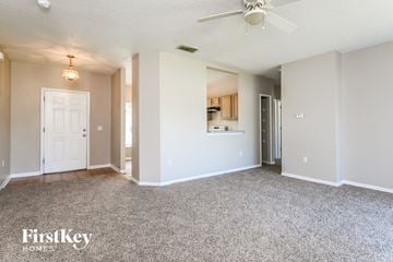 Kissimmee house for rent - a spacious living room with carpet and a ceiling fan