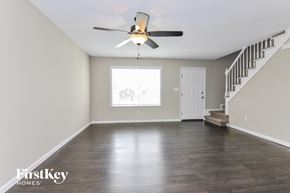 Lake Saint Louis house for rent - A spacious room with a staircase and a ceiling fan.