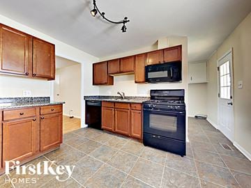 Streamwood house for rent - a kitchen with wooden cabinets and black appliances