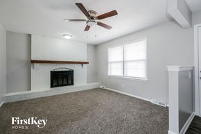 Lee's Summit house for rent - A spacious room with a fireplace and a ceiling fan.