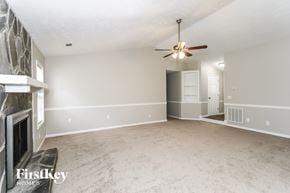 Woodstock house for rent - an empty living room with a fireplace and a ceiling fan
