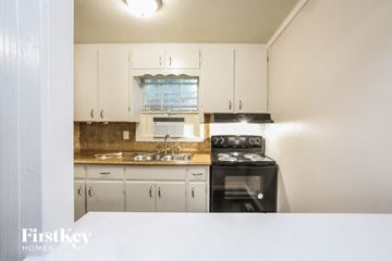 Kansas City house for rent - a kitchen with white cabinets and black appliances