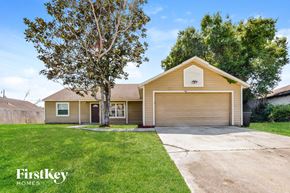 Deltona house for rent - a beige house with a driveway and a tree