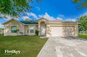 Poinciana house for rent - a beige house with a white garage door and a lawn