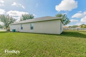 Poinciana house for rent - a small white house sitting in a grassy yard