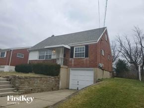 Cincinnati house for rent - A brick house with a garage door and a stone wall.