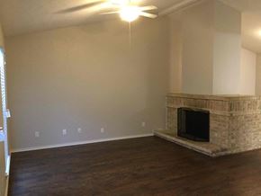 Forney house for rent - A living room with a fireplace and a ceiling fan.