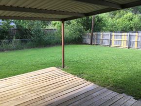 Forney house for rent - A wooden deck is in the foreground of a grassy area.