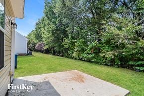 Huntersville house for rent - A backyard with a concrete slab and trees.