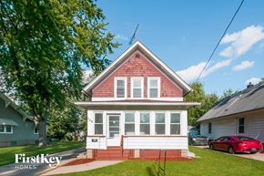 Aurora house for rent - A red brick house with a white porch and a red car parked in front.