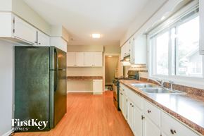 Aurora house for rent - A kitchen with a black fridge and wooden floors.