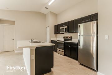 Port St. Lucie house for rent - a kitchen with stainless steel appliances and black cabinets