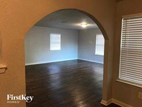 Burleson house for rent - A room with wooden floors and a large arched window.