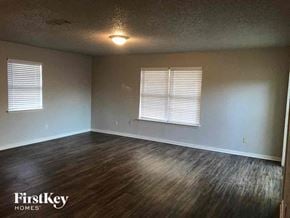 Burleson house for rent - A room with wooden floors and two windows with blinds.