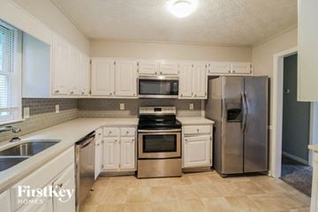 Lithonia house for rent - a kitchen with white cabinets and stainless steel appliances