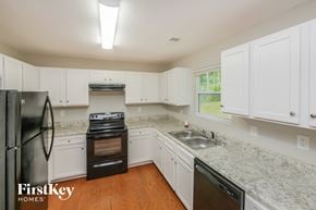 Senoia house for rent - a kitchen with white cabinets and granite counter tops and black appliances