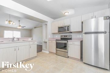 Palm Bay house for rent - a kitchen with white cabinets and stainless steel appliances