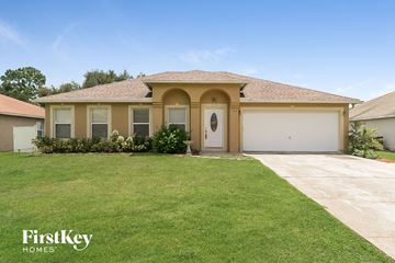 Poinciana house for rent - a beige house with a garage door and a lawn