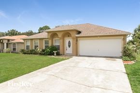 Poinciana house for rent - a beige house with a white garage door and a lawn