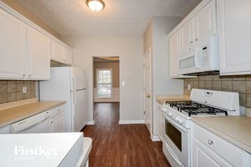 Mcdonough house for rent - a kitchen with white cabinets and white appliances and wood floors