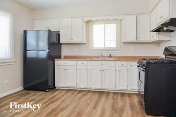 Calumet City house for rent - a kitchen with white cabinets and a black refrigerator