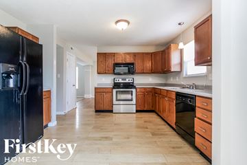 Brownsburg house for rent - A kitchen with wooden cabinets and a black fridge.