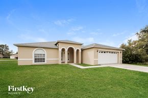 Kissimmee house for rent - a beige house with a garage and a green lawn