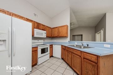 Kissimmee house for rent - a kitchen with white appliances and wooden cabinets
