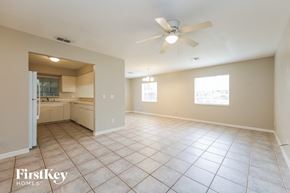 Lehigh Acres house for rent - an empty living room and kitchen with a ceiling fan