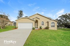 Lake Wales house for rent - a beige house with a white garage door and a lawn