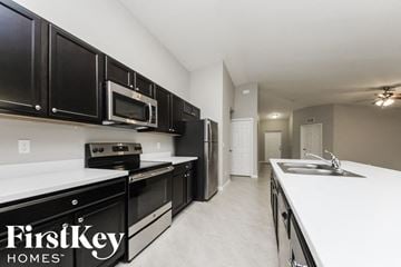 Port St. Lucie house for rent - a kitchen with black cabinets and white counter tops and a sink