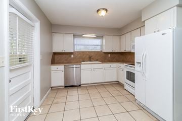 Orlando house for rent - a kitchen with white cabinets and white appliances and tiled floors