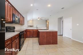 Anna house for rent - a kitchen with wooden cabinets and a black stove and a sink