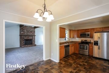 Gladstone house for rent - A kitchen with wooden cabinets and a stone fireplace.