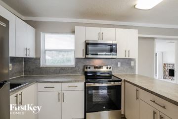 Fort Lauderdale house for rent - a kitchen with white cabinets and a stove and a microwave