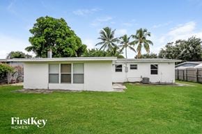 Fort Lauderdale house for rent - a small white house with a grass yard and palm trees