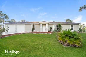 Lehigh Acres house for rent - a home with a lawn and palm tree in front of it